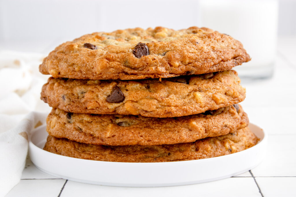 four giant chocolate chip cookies stacked on a plate