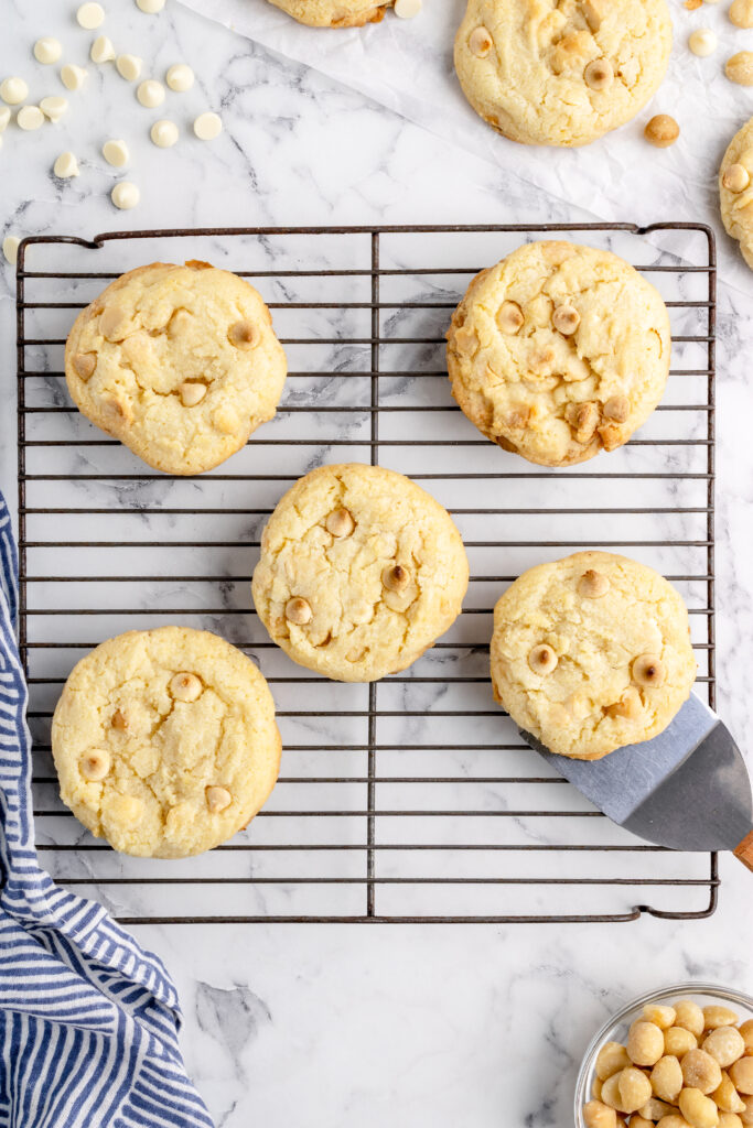 macadamia nut cookies on a cooling rack with a cookie spatula