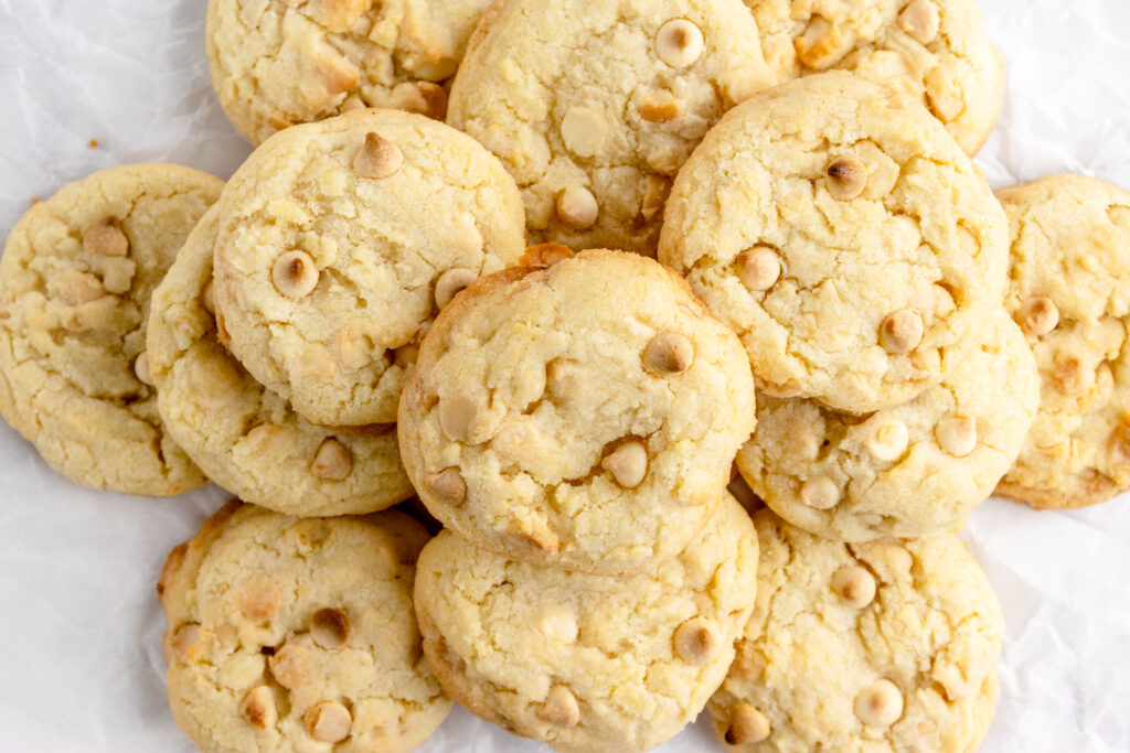 pile of white chocolate cookies on a piece of crinkled parchment paper