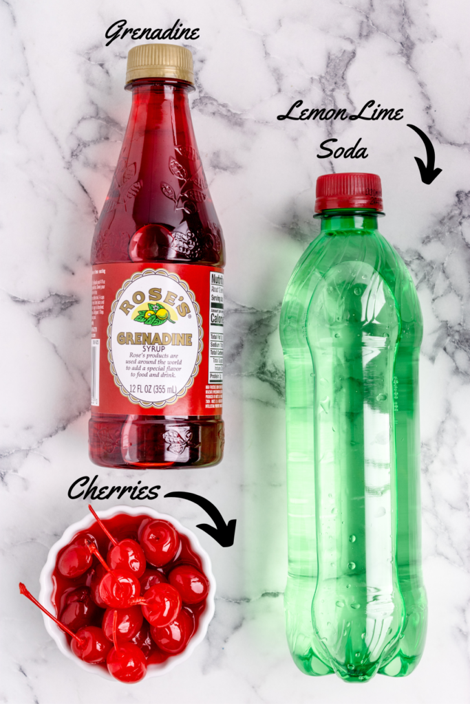 ingredient shot of shirley temple drink overhead image of lemon lime soda bottle, a bowl of cherries and a bottle of grenadine syrup